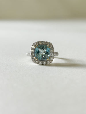 A beautiful cushion cut aquamarine and diamond cluster ring, set into white gold, with yellow gold claws over the aquamarine.
