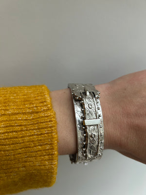 Buckle bangle, on model's wrist, with mustard yellow jumper sleeve visible.