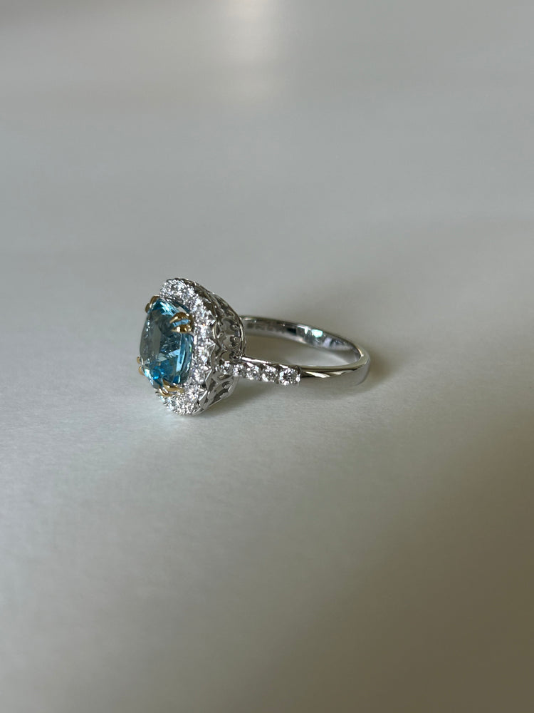 Cushion cut aquamarine & diamond cluster ring, in 18ct white gold, with contrasting yellow gold claws.  Side view.