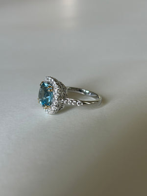 Cushion cut aquamarine & diamond cluster ring, in 18ct white gold, with contrasting yellow gold claws.  Side view.
