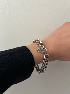 Silver curb bracelet worn on model's wrist, close up photo