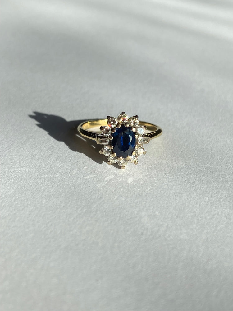 Midnight blue sapphire cluster ring with round and baguette cut diamonds